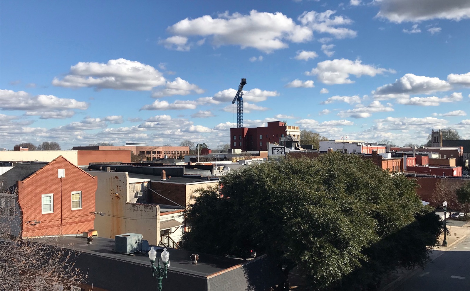 Rooftops and low brick buildings of downtown Concord, North Carolina, with the painted Ritchie Hardware Co. wall sign and a church steeple on the skyline